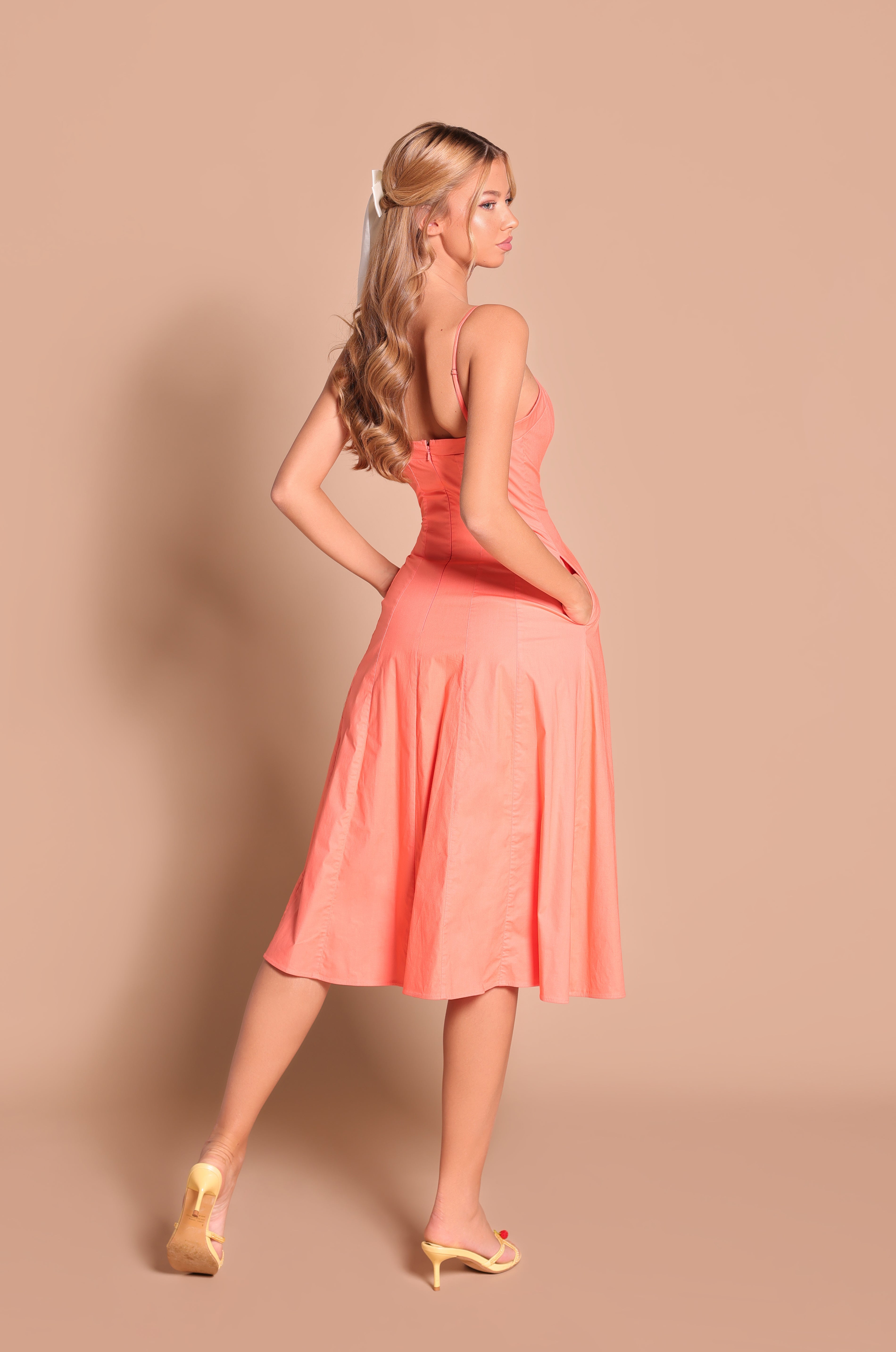 Woman with long blonde hair in yellow heels poses with one hand on her hip, wearing the Papaya Midi Casual Summer Dress: Auberine against a beige background.